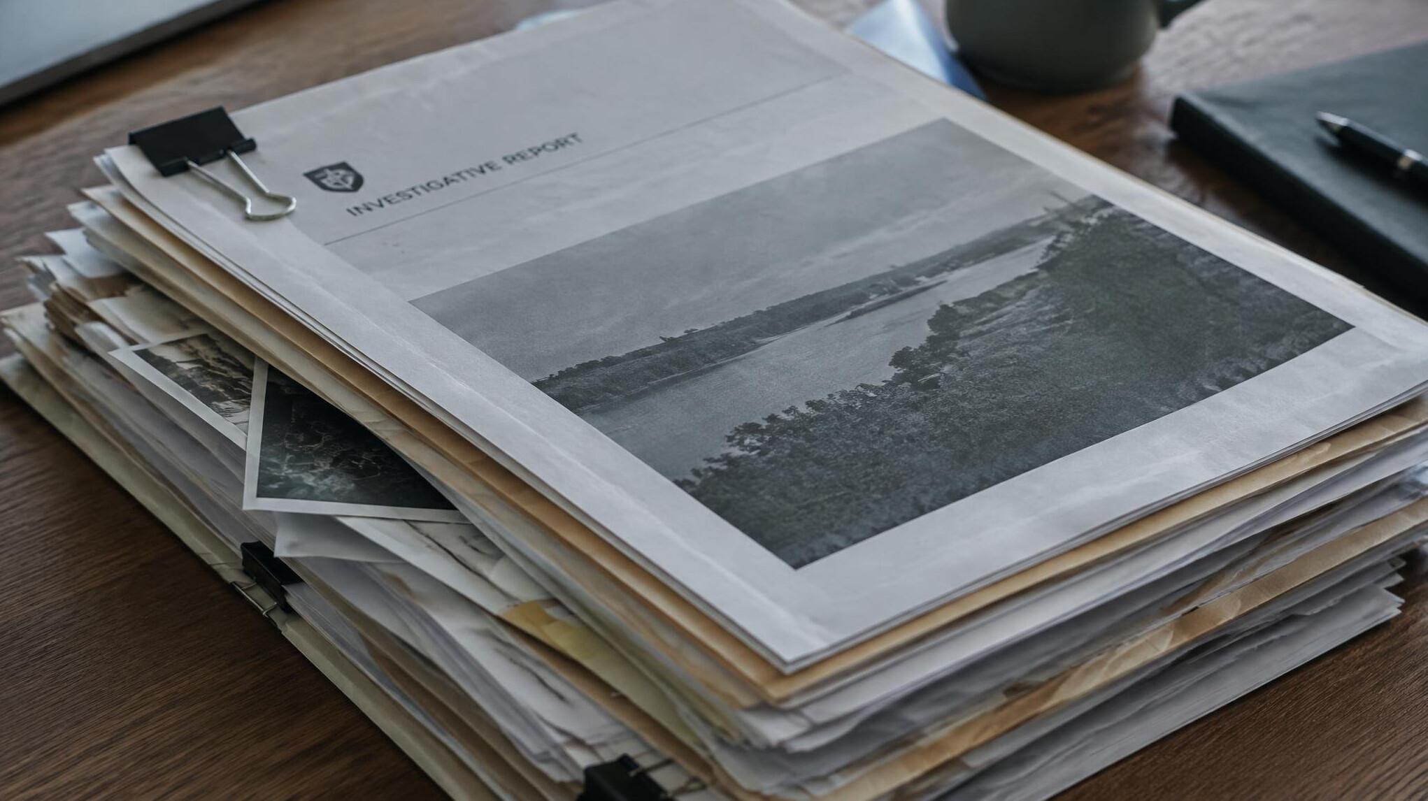 Stack of printed investigative reports and documents on a desk